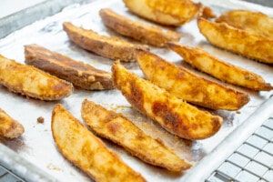 crispy seasoned potato wedges lined up on a foil lined pan