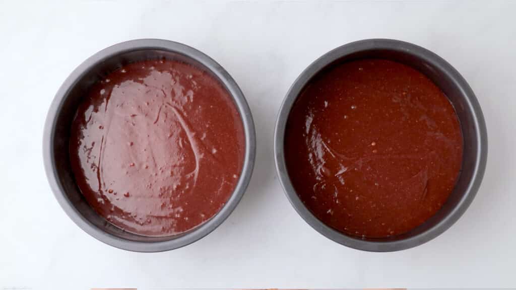 gluten free red velvet cake batter in metal pans on a white table ready to bake