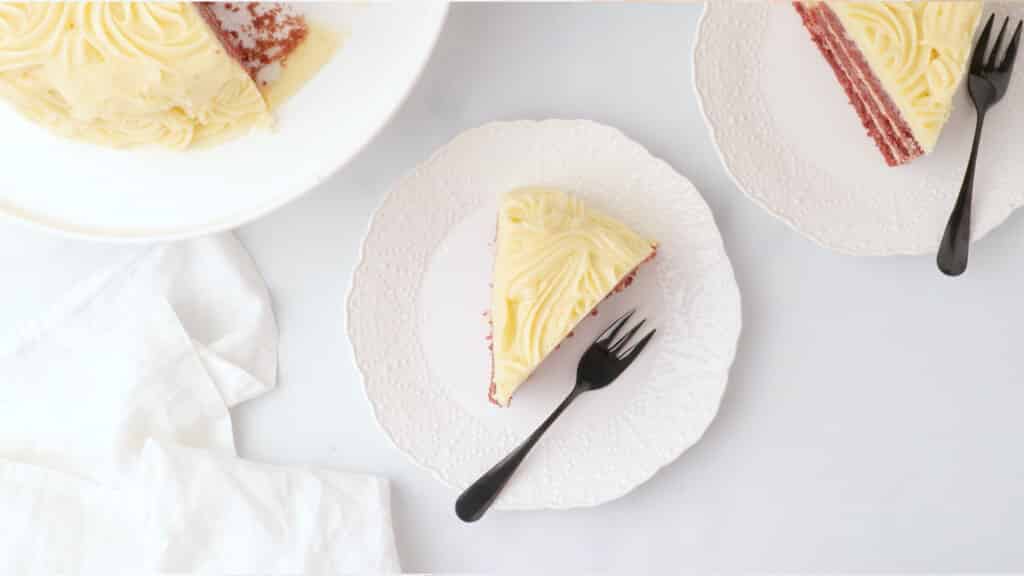 overhead view of slice of gluten free red velvet cake with cream cheese frosting on a white plate