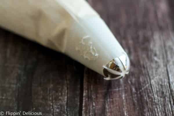 Cream cheese frosting in a drop flower piping bag for gluten free red velvet cake