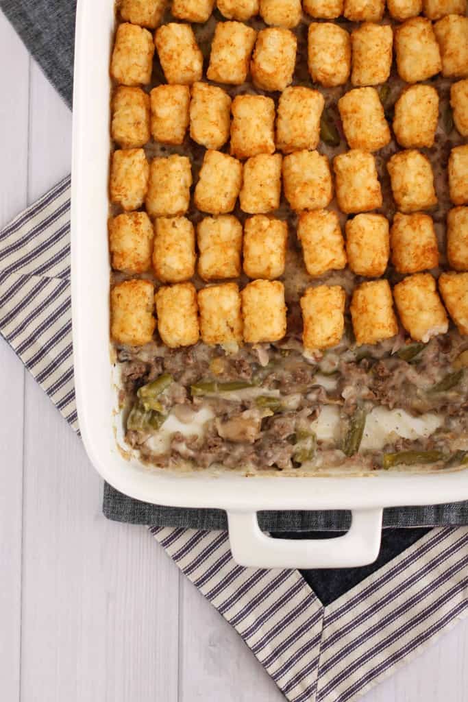 overhead gluten free tater tot casserole made with gluten free cream of mushroom soup in a white casserole dish with ground turkey 