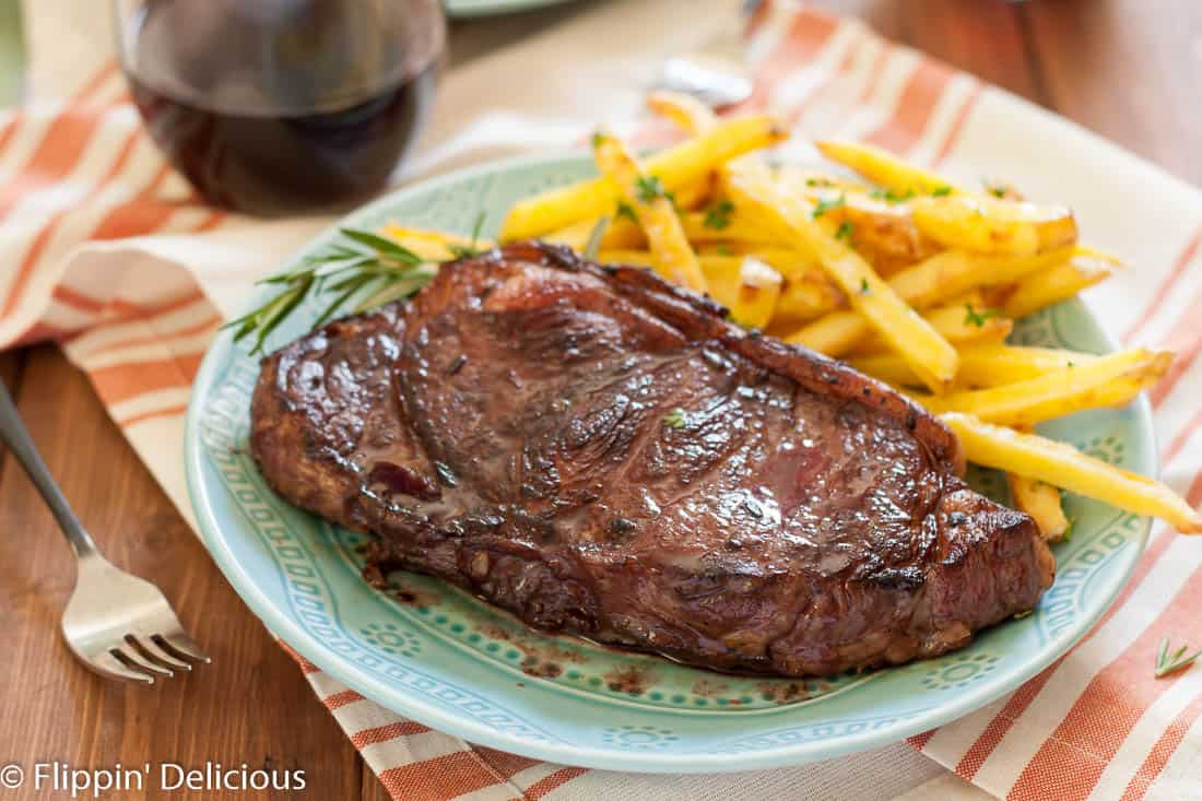 Juicy new york strip steaks marinated in red wine, rosemary, garlic and shallots with garlic and herb baked fries make a perfect at home date!