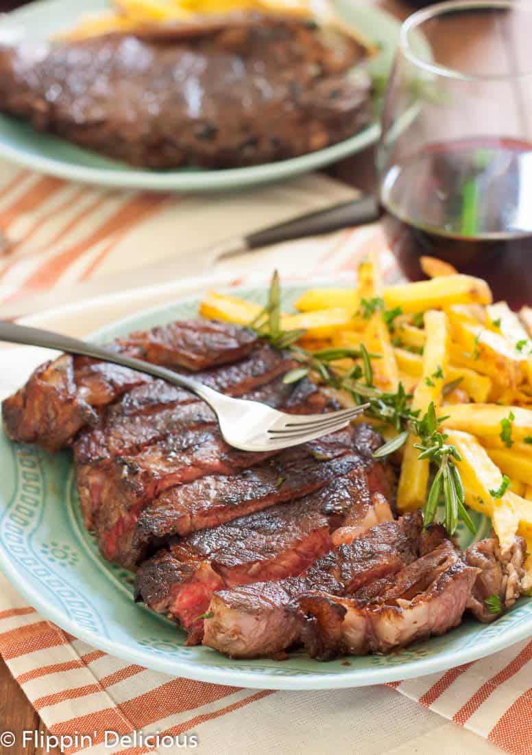Juicy new york strip steaks marinated in red wine, rosemary, garlic and shallots with garlic and herb baked fries make a perfect at home date!