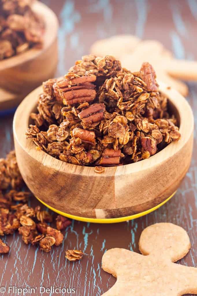 Gluten Free Gingerbread Granola takes just a few minutes to mix up, has only 9 ingredient and is perfectly spicy and sweet! If you are a granola fan, you are in for a special treat! When I was growing up my family almost always had a cannister full of homemade granola. Our recipe was simple and we made it exactly the same way every time. Oats, honey, oil, molasses, coconut, sunflower seeds, water, and wheat germ. I remember measuring the ingredients with my mom. We'd mix them all together in our biggest metal mixing bowl, and then we would bake the granola for several hours IN our mixing bowl, stopping to give it a big stir every 20 minutes or so. I actually hated eating the granola. I hated the sunflower seeds and would pick them all out before adding milk to my bowl. As you can imagine that made breakfast take a LONG time! As I grew up I was astounded at the different homemade granola recipes that people create! On Flippin' Delicious I have gluten free oatmeal cookie granola, gluten free salted caramel granola and gluten free pumpkin granola recipes. My granola recipe repetiore pales in comparison to the granola recipe arsenal that Leah from Grain Changer has on her blog. Just a few days ago she shared a recipe for Apple Pie Granola! Leah loves granola, which is why some of my friends and I have gathered to shower her and her new baby with granola recipes! Granola Baby Shower Oat Free Granola from There is Life After Wheat Gluten Free Gingerbread Granola from ME Lemon Blueberry Granola from Thoroughly Nourished Life Maple Walnut Cinnamon Granola from Fit Mitten Kitchen Chai Spiced Granola from Fresh April Flours Coconut Granola from The Emotional Baker Tropical Hempseed Granola from A Clean Bake I brought this gluten free gingerbread granola to the party. It takes just a few minutes and 9 ingredients to make this sweet and spicy ginger granola. I add extra ginger to mine because I like it spicy like my favorite gingersnaps. If you are a fan of satisfying clumps in your granola be sure to wait to stir the granola until after it has cooled completely. Gluten Free Gingerbread Granola Author:  Prep time: 5 mins Cook time: 25 mins Total time: 30 mins Serves: 4 cups Gluten Free Gingerbread Granola takes just a few minutes to mix up, has only 9 ingredient and is perfectly spicy and sweet! Ingredients 3 cups certified gluten free oats (purity protocol) 1 cup coarsely chopped pecans 2-3 Tablepsoons ground flax seed (optional) 1 teaspoon ground ginger (I used 1 ½ teaspoons because I like mine really spicy) ½ teaspoon cinnamon pinch ground cloves ¼ cup coconut oil ¼ cup molasses ¼ cup honey Optional, gingerbread men (I used GF Jules graham cracker mix) Instructions Preheat your oven to 325F. Line a baking sheet with parchment paper or a silicone baking mat. In a large bowl combine the oats, pecans, flax meal(if using) and spices. In a small bowl mix (or large liquid measuring cup) combine the oil, molasses, and honey. Pour the liquid mixture over the oats and stir until evenly coated. Spread evenly over the baking sheet and bake for 20-25 minutes, stirring once at about 15 minutes. Let cool, break into bite sized clumps. Serve with gingerbread men, if you want.