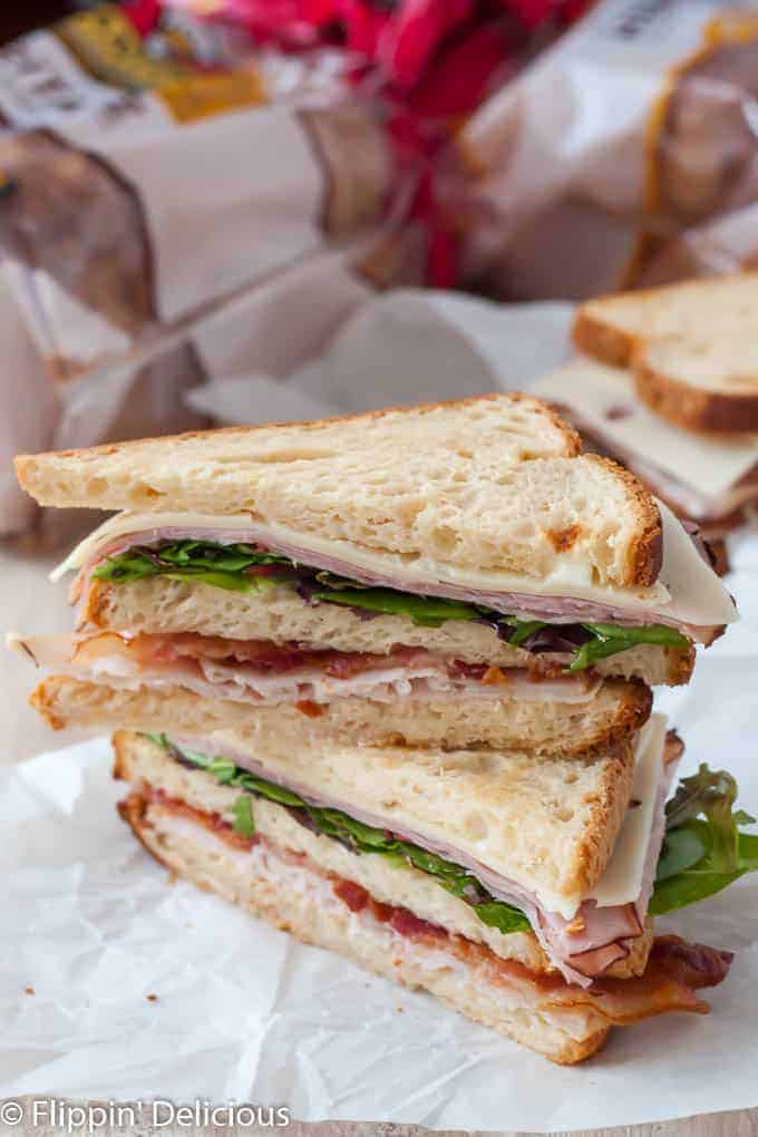  gluten free club sandwich with bacon, turkey, ham, canyon gluten free bread, cut in half on diagonal and stack of each other