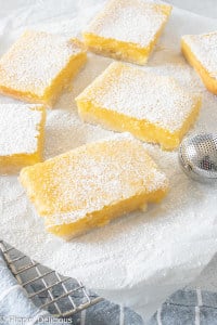 gluten free lemon squares on a white napkin, all sprinkled with powdered sugar