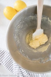 creamed butter, powdered sugar, and egg white in a metal bowl with a rubber spatula with a wooden handle