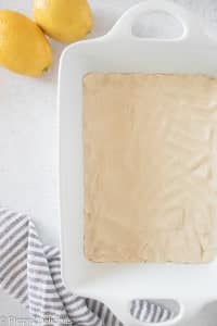 gluten free shortbread crust pressed in a white ceramic baking dish to make lemon bars