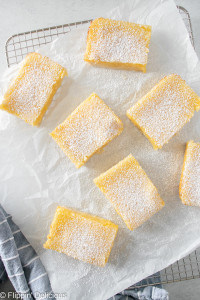overhead picture of 7 gluten free lemon bars on a white napkin on a metal cooling rack
