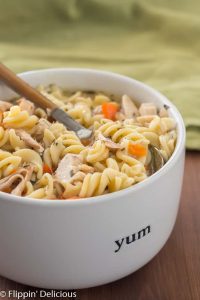 Instant Pot gluten free chicken noodle soup in white bowl with wood handle spoon