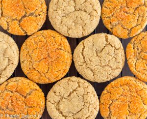 Overhead photo of vegan gluten free pumpkin sugar cookies on a black cooling rack, half sprinkled with orange sanding sugar and half with coarse raw sugar