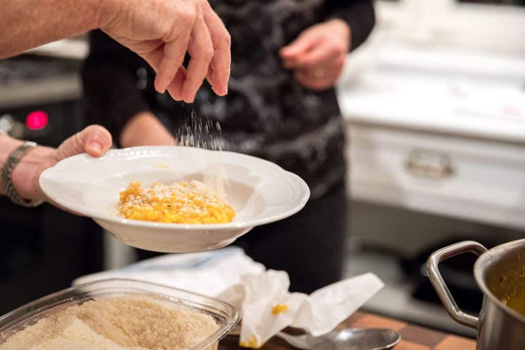 hand sprinkling parmesan on pumpkin risotto