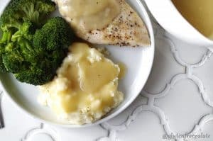 gluten free gravy over mashed potatoes and chicken breast beside broccoli on white plate