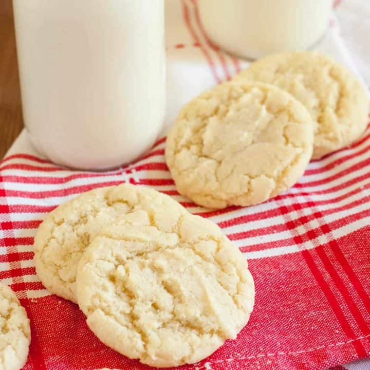 gluten free sugar cookies on a red plaid napkin next to glass of milk