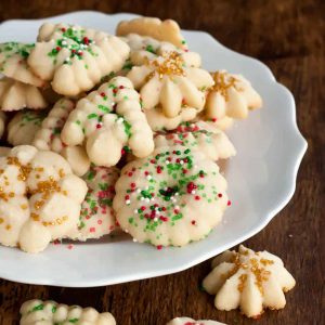 gluten free spritz cookies with red, green, white, and gold sprinkles for the holidays on a white plate