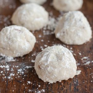 gluten free snowball cookies (also known as mexican wedding cookies or russian tea cakes) on a wooden table with powdered sugar
