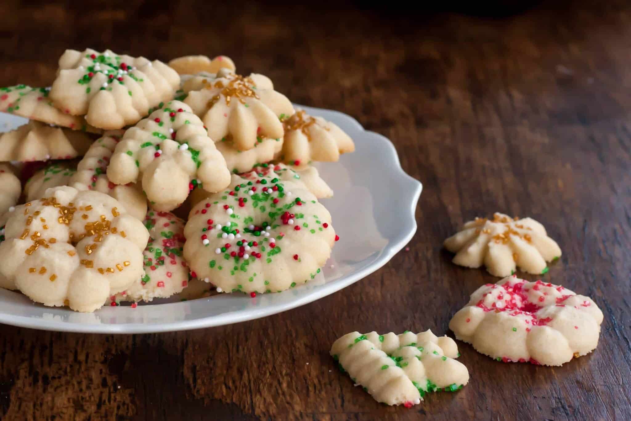 gluten free spritz cookies with red, green, white, and gold sprinkles for the holidays on a white plate 