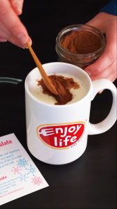 adding vegan hot chocolate mix to dairy free milk in white mug