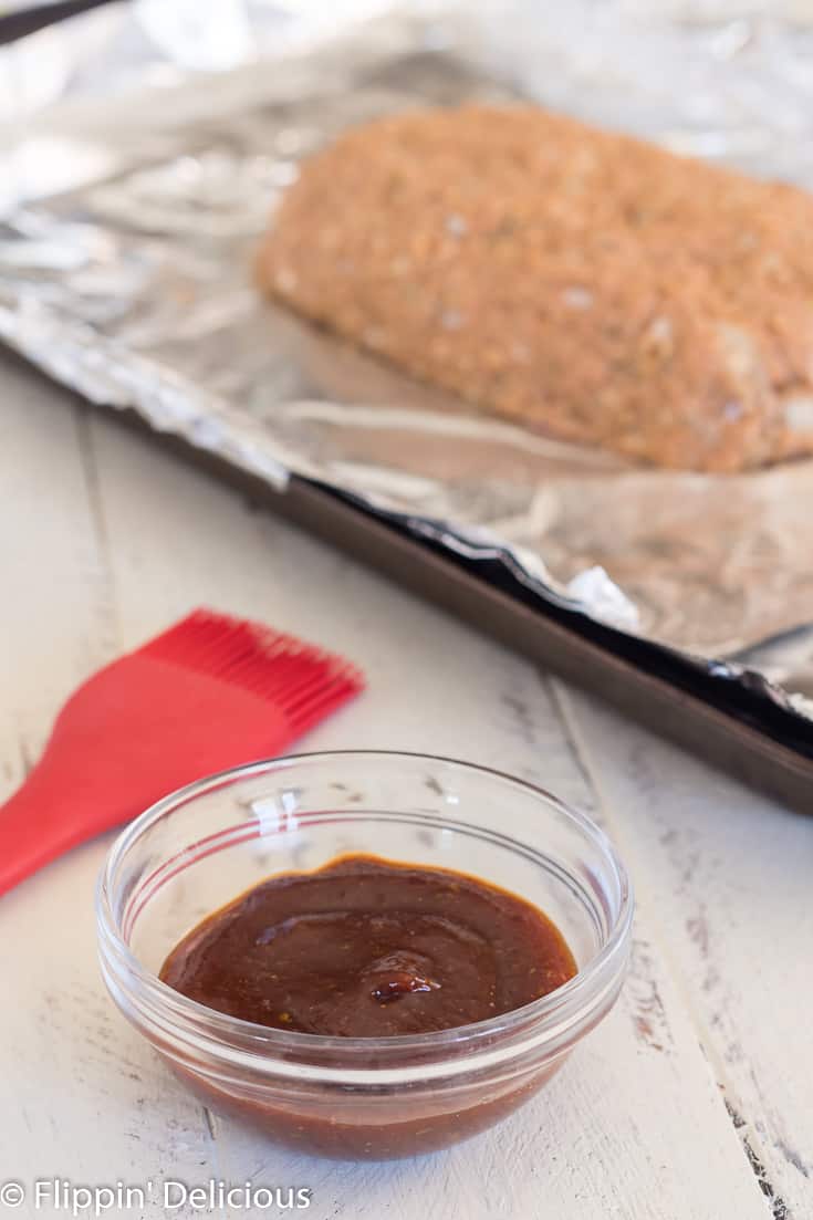 meatloaf glaze in front of gluten free turkey meatloaf on a aluminum foil lined baking sheet