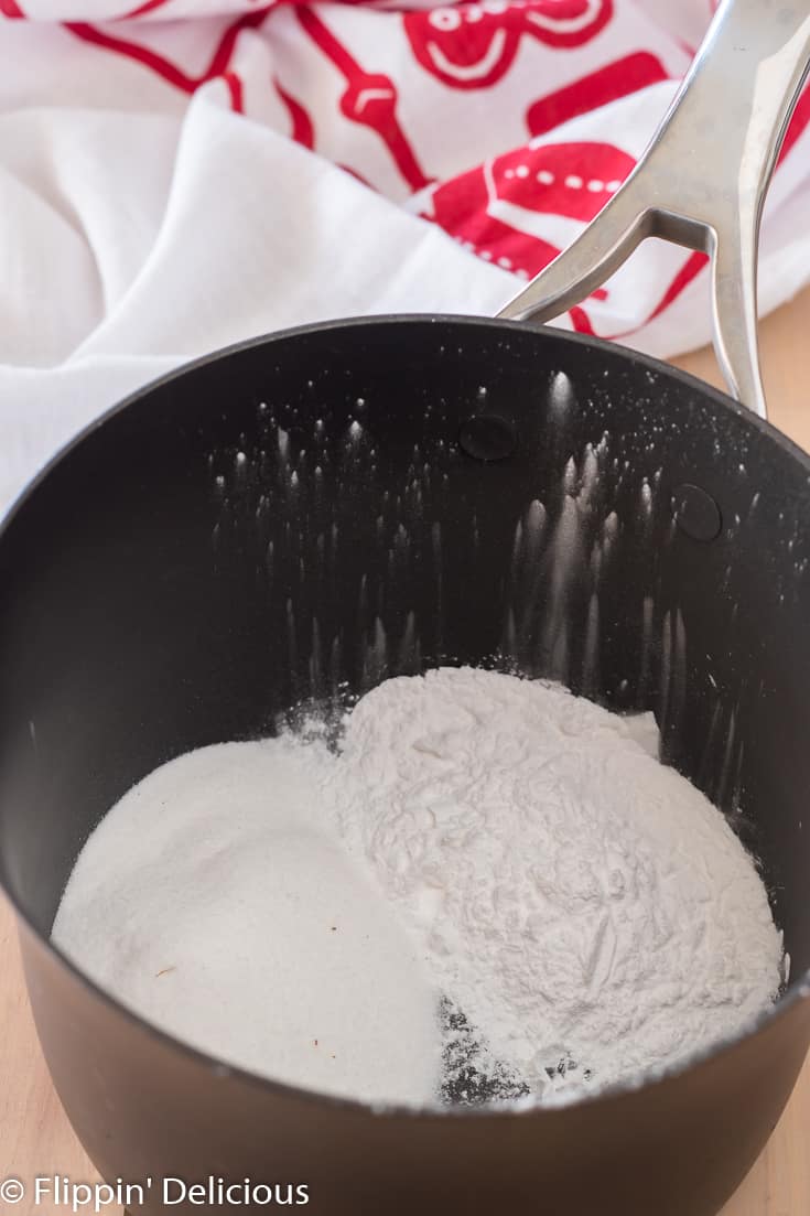 saucepan with cornstarch and sugar to make gluten free pudding with a red and white dish towel in the background