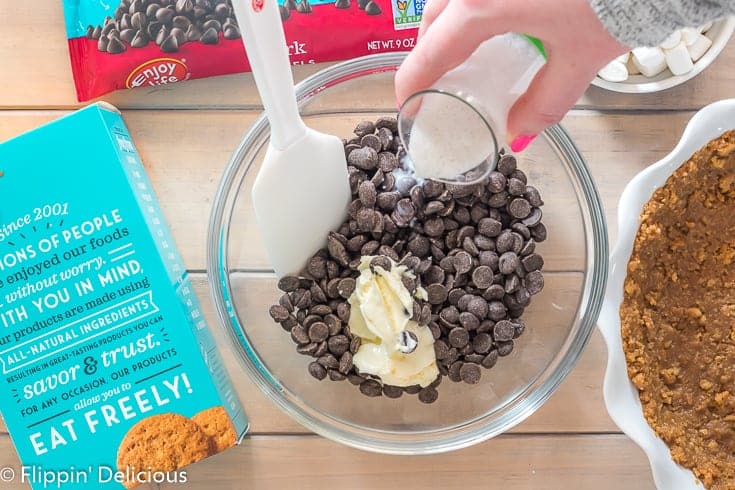 pouring dairy free milk into a glass bowl filled with enjoy life dark morsels and vegan butter