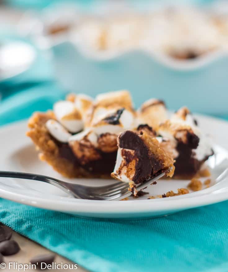 bite of dairy free gluten free smores pie on a fork on a white plate with a teal dish towel
