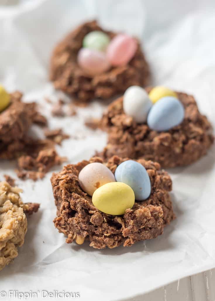 chocolate sunflower seed butter oatmeal gluten free no bake cookie birds nest with chocolate eggs inside on a white parchement paper