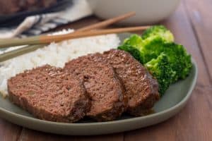 gluten free instant pot meatloaf glazed with teriyaki on a green plate with rice and broccoli