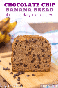 loaf of gluten free banana bread with chocolate chips on a cutting board with ripe bananas in the background with text "chocolate chip banana bread gluten-free| dairy-free| one-bowl"