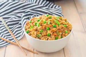 bowl of gluten free turkey fried rice with chopsticks and a striped dish towel