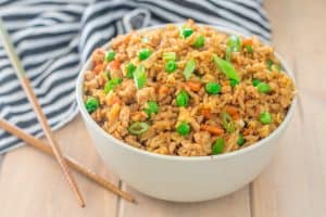 close up of bowl of gluten free turkey fried rice with peas, chopped carrots and green onions made with gluten free tamari sauce