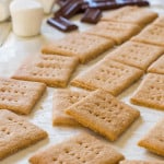 gluten free graham crackers on a piece of parchment paper with chocolate and marshmallows in the background.