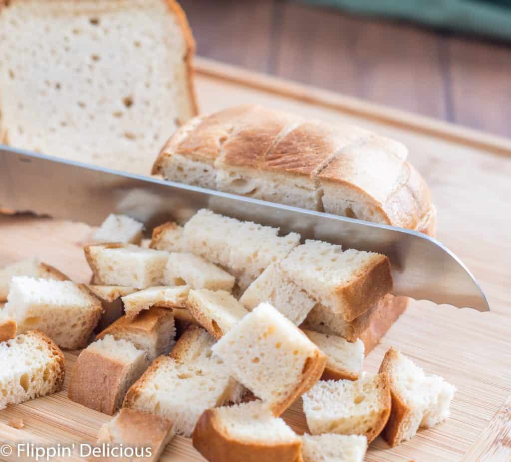 knife cutting gluten free bread into cubes for gluten free stuffing