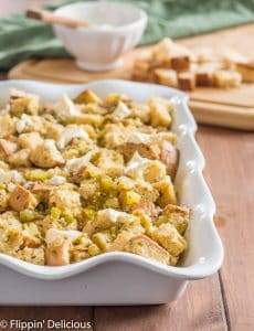 gluten free stuffing with green chile dotted with butter and ready to bake in a white casserole dish