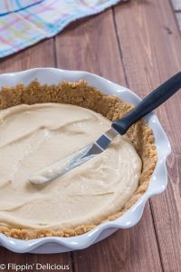 spreading vegan pudding into a pie crust ith an offset spatula