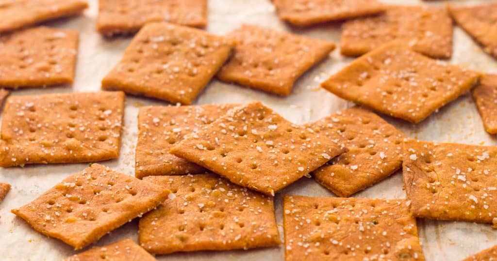 square light red gluten free pizza crackers on a sheet pan lined with parchment paper