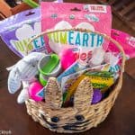 inside of an allergy friendly easter basket with markers, water bottles, art supplies, stickers, stuffed bunny toy, and yumearth candy