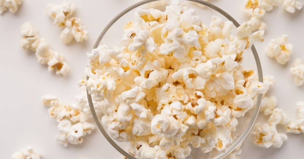 popped popcorn in a glass bowl on a white table