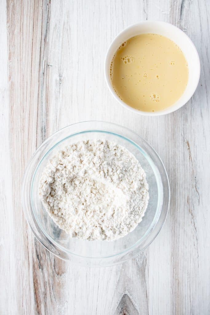 wet and dry ingredients for gluten free dumplings in bowls on a white wooden backdrop