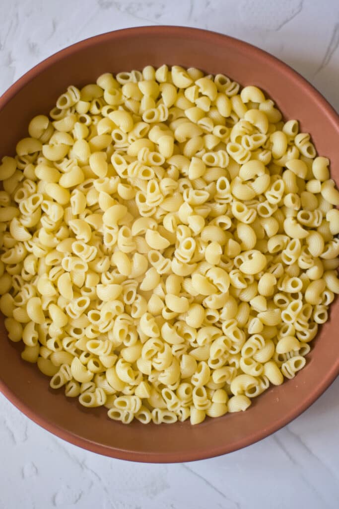 gluten free macaroni elbow pasta in a brown bowl on a marble counter