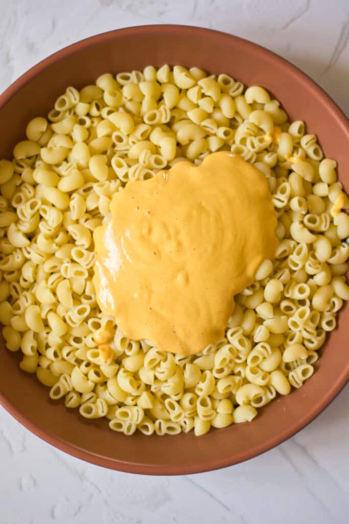 vegan cheese sauce poured over gluten free macaroni pasta