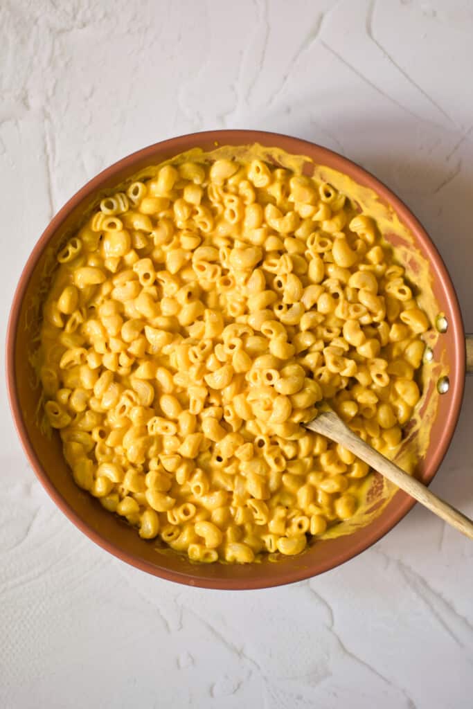 serving bowl with gluten free dairy free macaroni and cheese with a wooden serving spoon on a white table