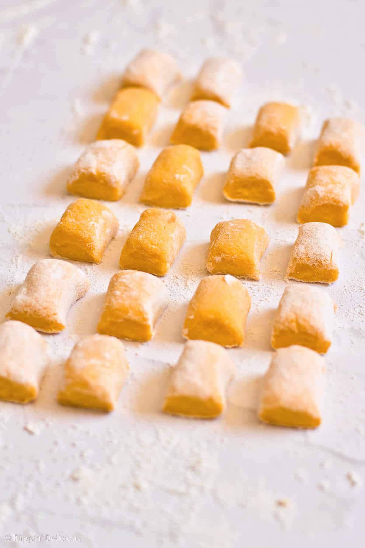 gluten free pumpkin gnocchi pieces ready to be shaped, sitting on a marble table