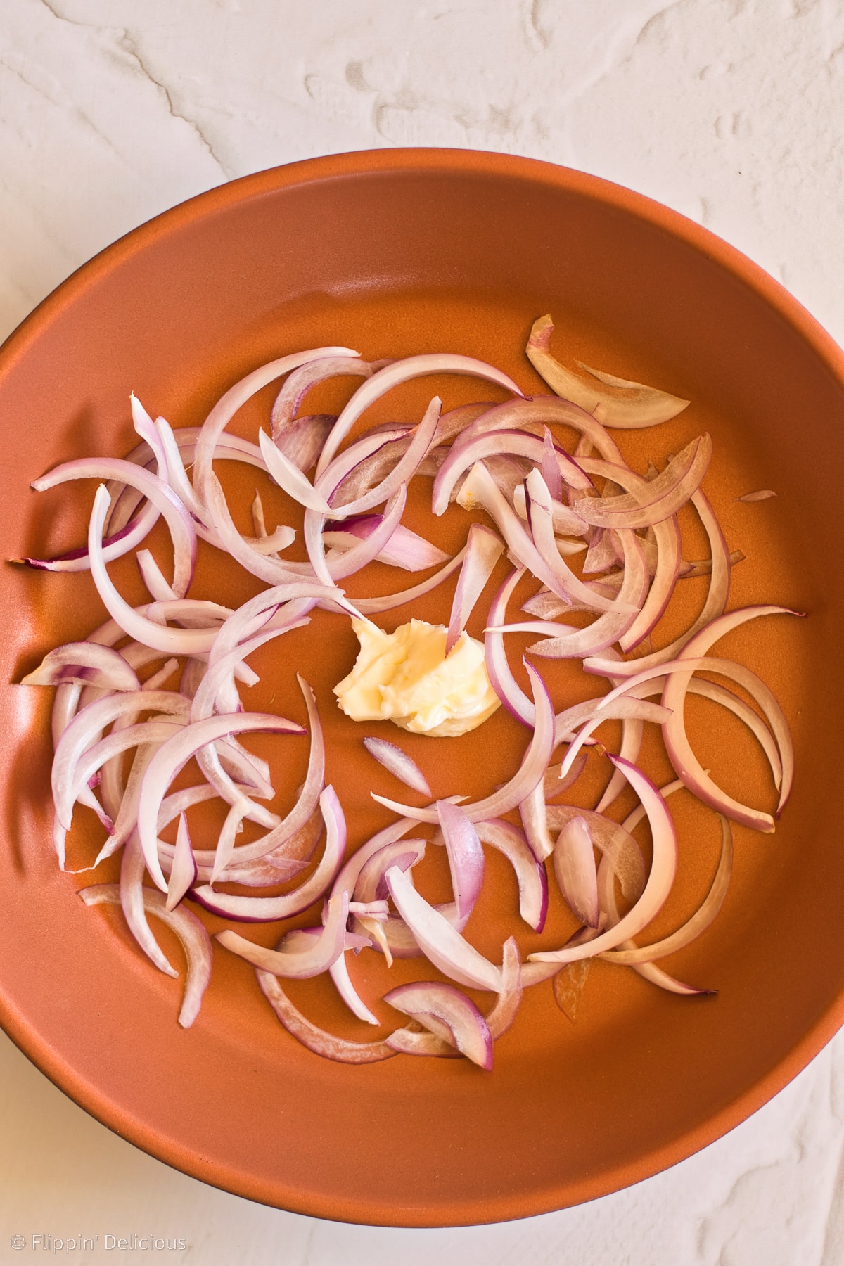 Copper pan with onions and vegan butter