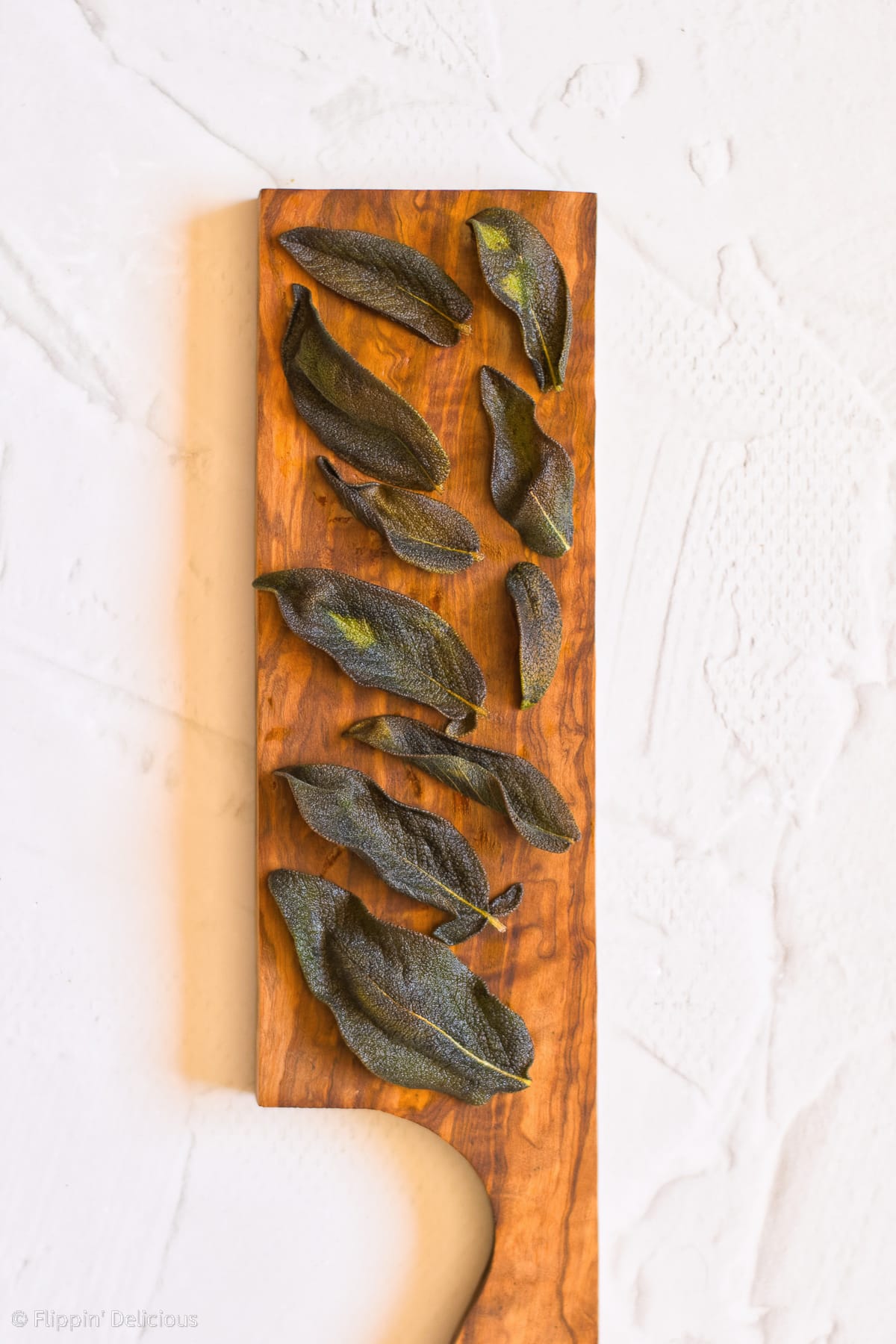 fried sage on a wooden cutting board on a marble table top