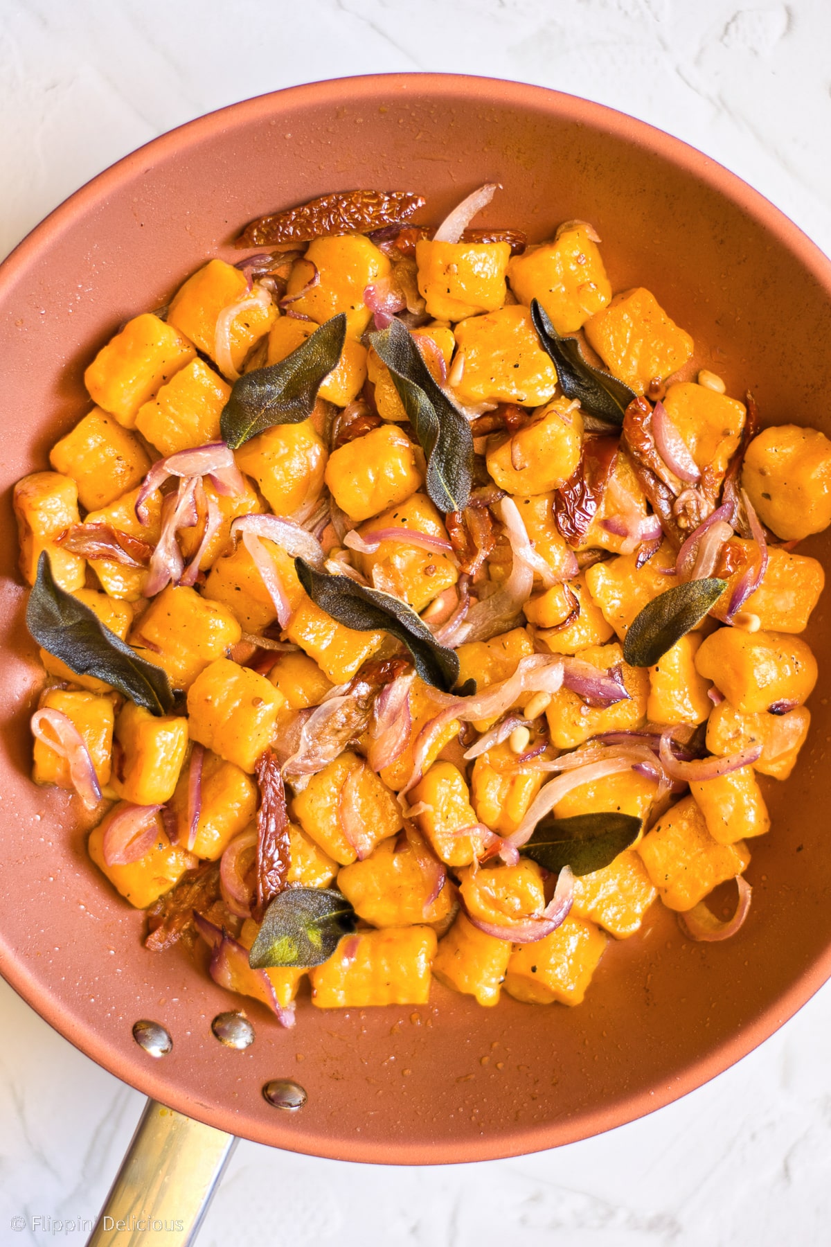 photo of copper frying pan with gluten free gnocchi with red onions and fried sage