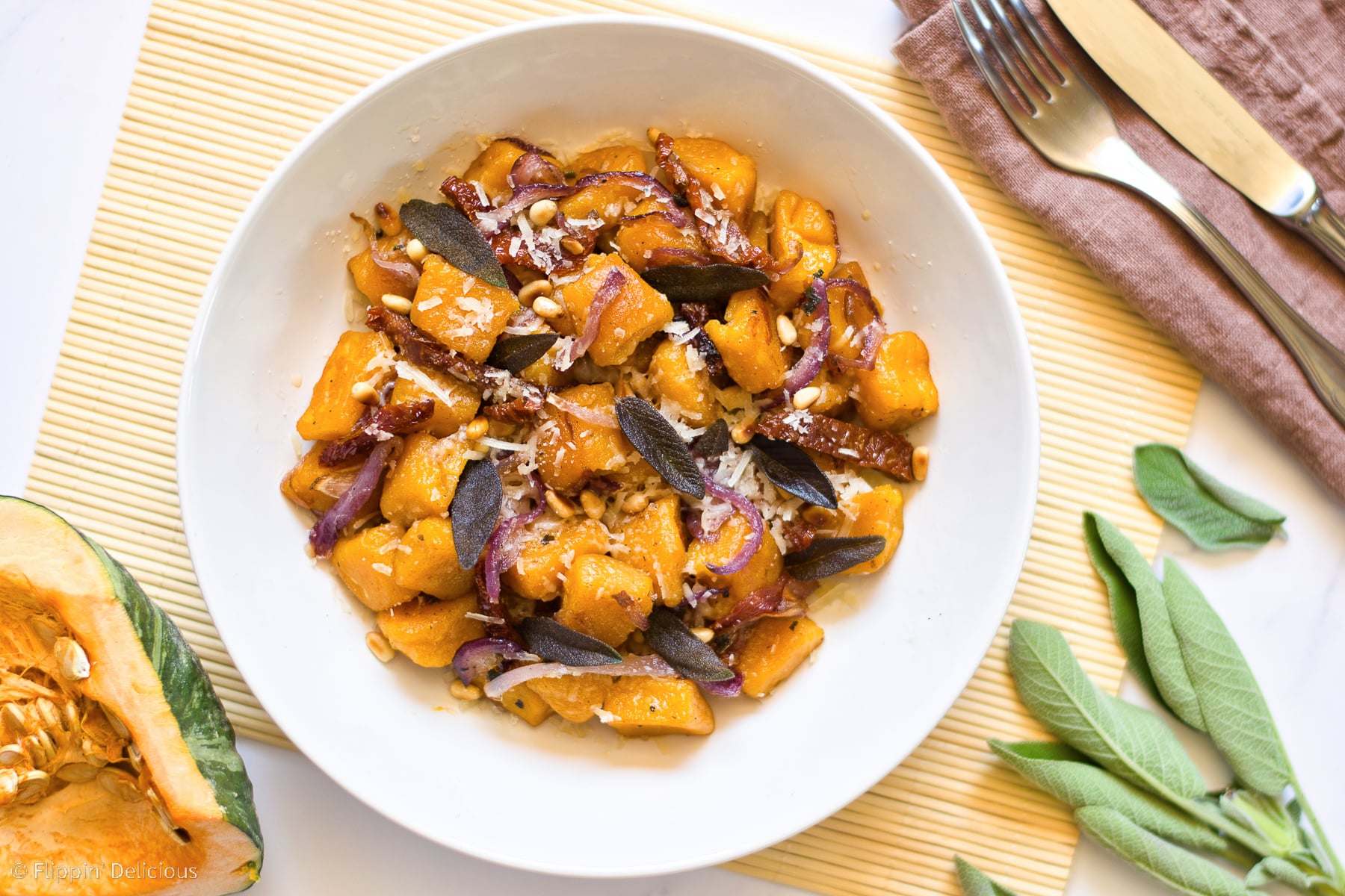 white bowl of pumpkin gnocchi with sage and sundried tomato sauce