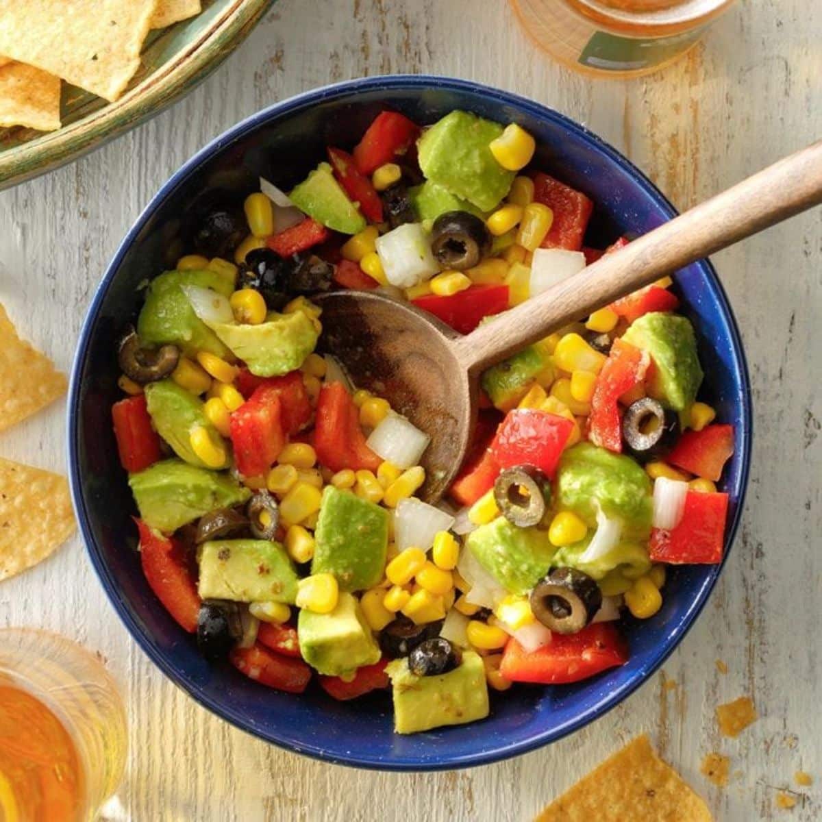 Avocado Dip in a blue bowl with a wooden spoon.