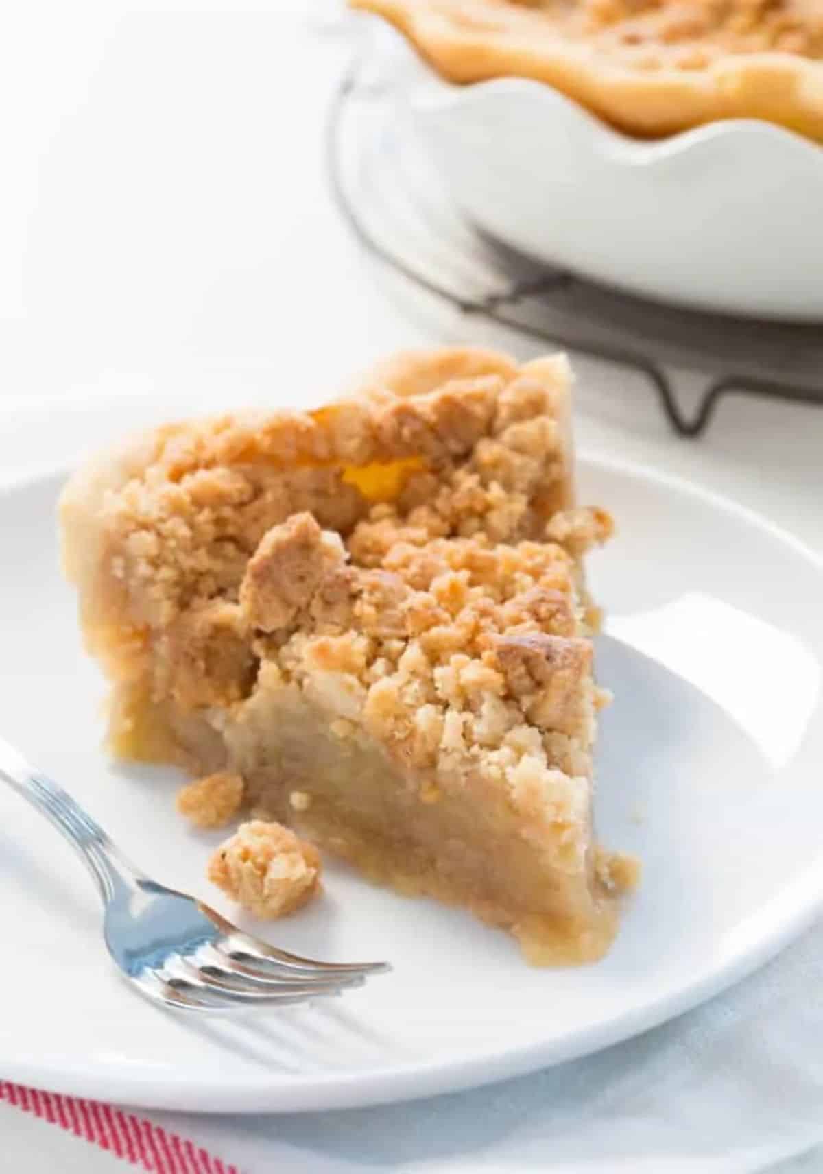 A piece of Gluten-Free Dutch Apple Pie with a Sweet Crumb Topping on a white plate with a fork.