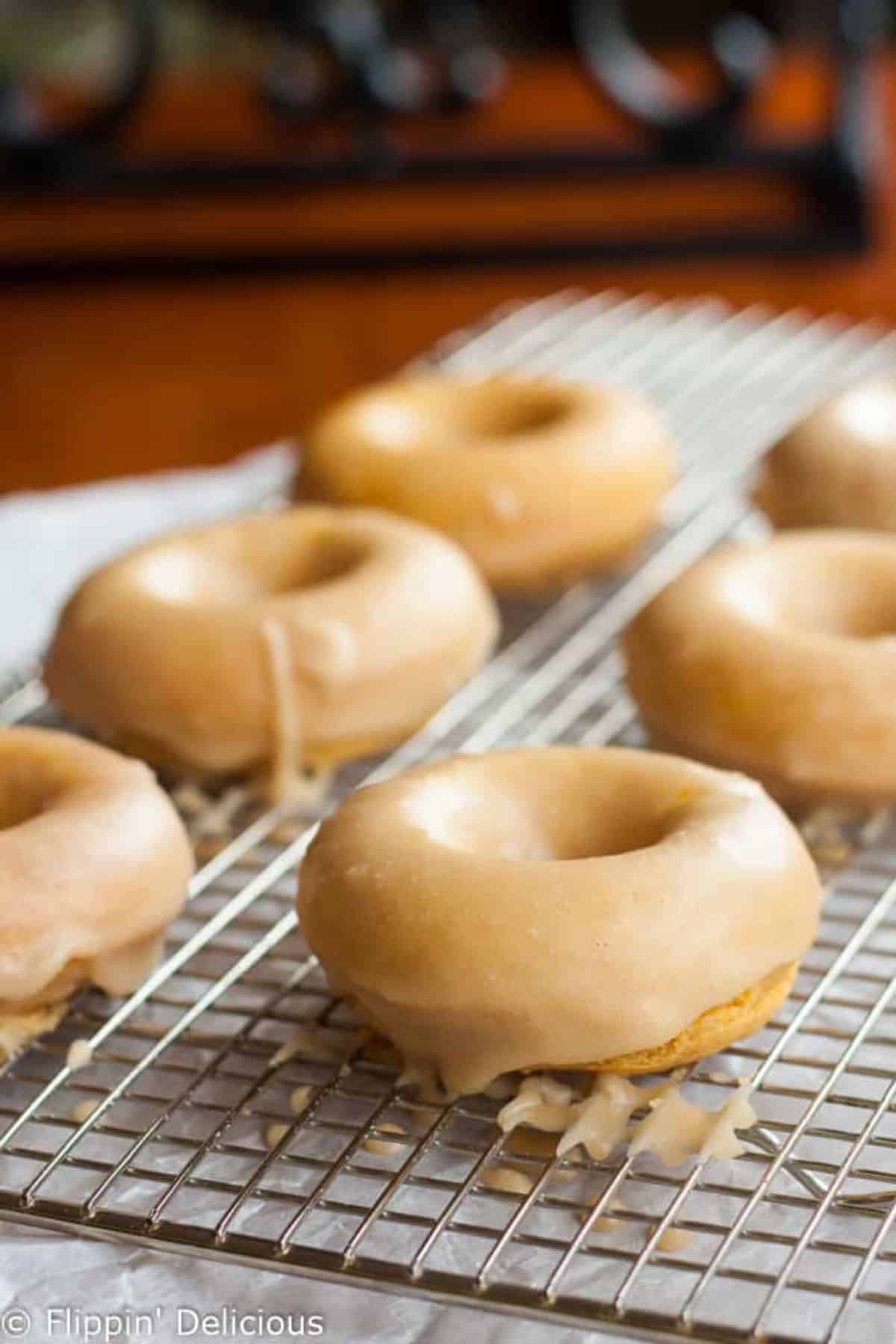 Gluten-free Pumpkin Donuts with Maple Glaze on a baking grid.